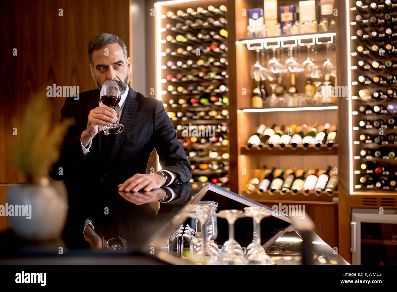 Handsome elegant businessman drinking red wine in bar Stock Photo - Alamy