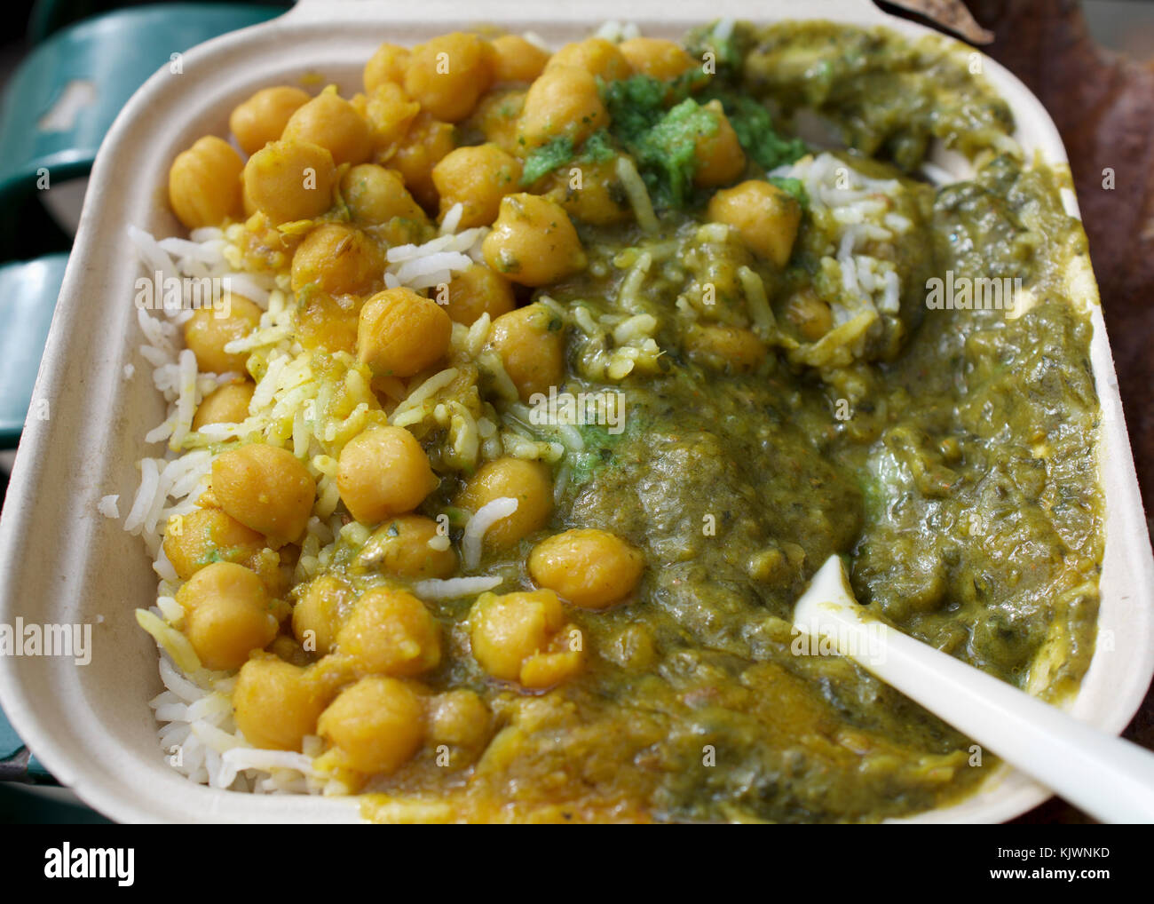 Closeup on veggie Indian dish rice, chickpeas and spinach curry on rice in carryout box over