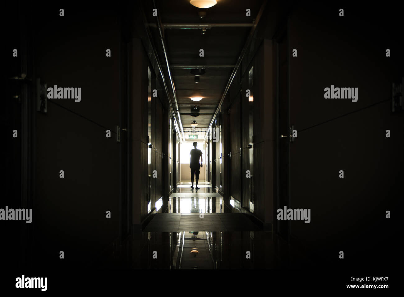 Man walking down a long dark corridor Stock Photo