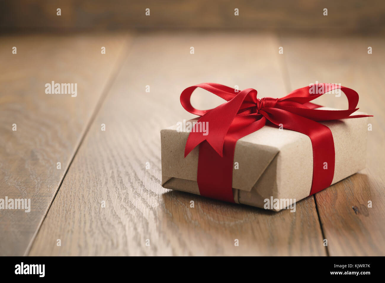 brown paper gift box with red ribbon bow on oak table Stock Photo Alamy