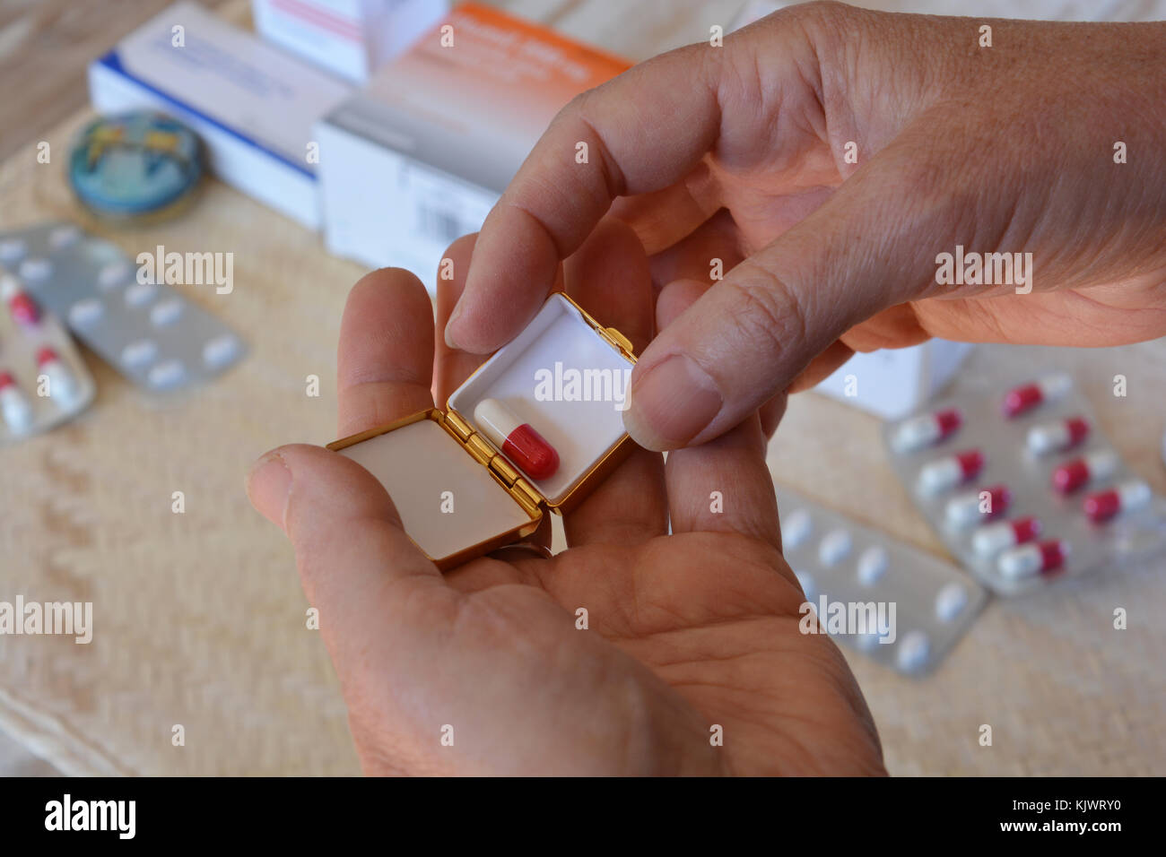 Putting a gel capsule in to a pill box,  to be taken later Stock Photo