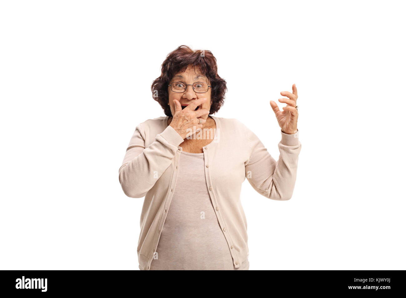 Surprised senior lady covering her mouth with her hand and looking at the camera isolated on white background Stock Photo