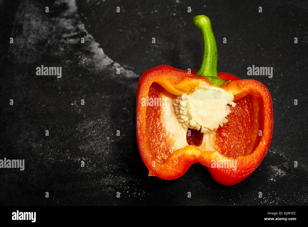 Half cut red bell pepper on a dark slate background, selective focus, space for text. Stock Photo