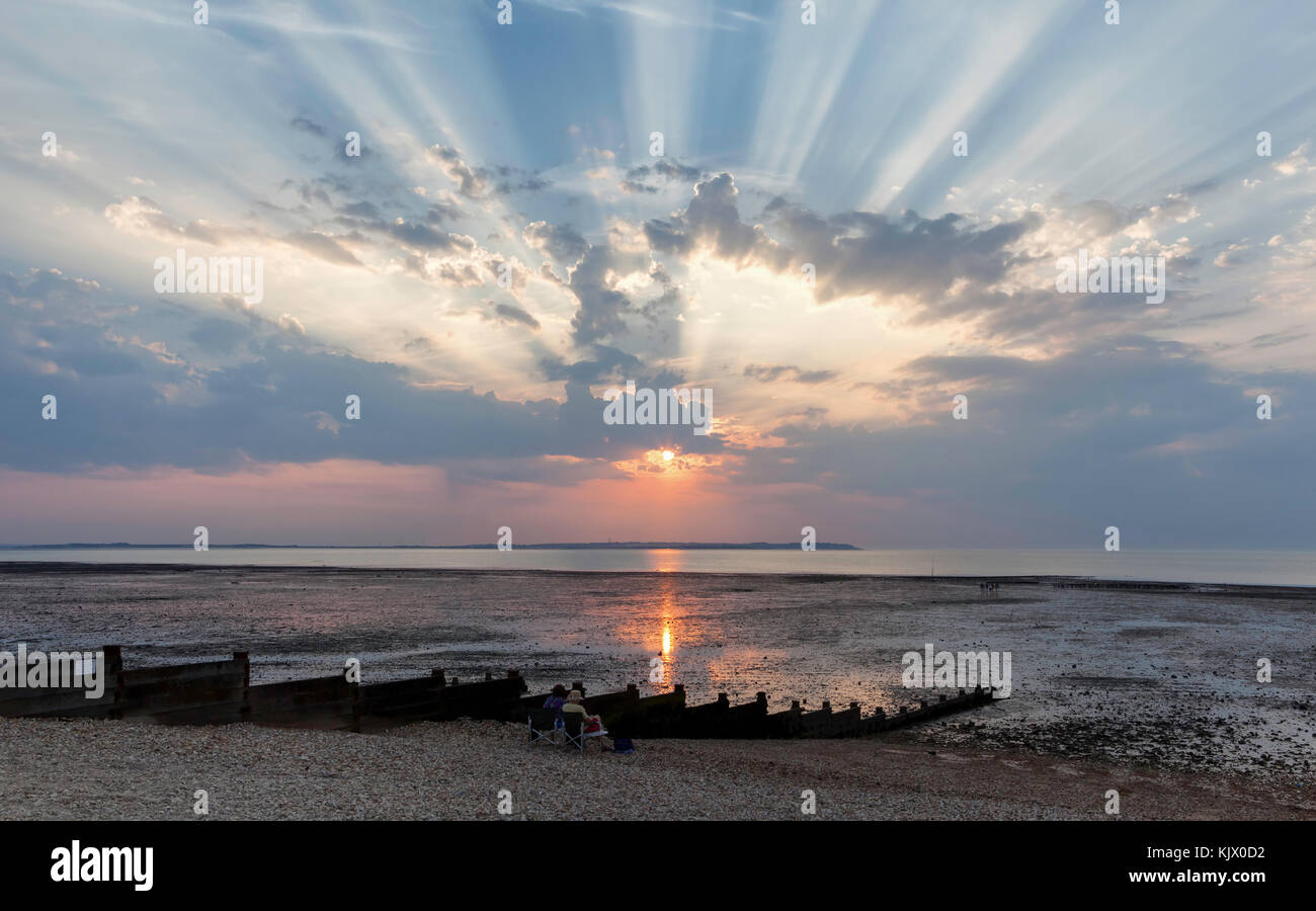 Crepuscular rays over Whitstable beach and the Isle of Sheppey. Stock Photo