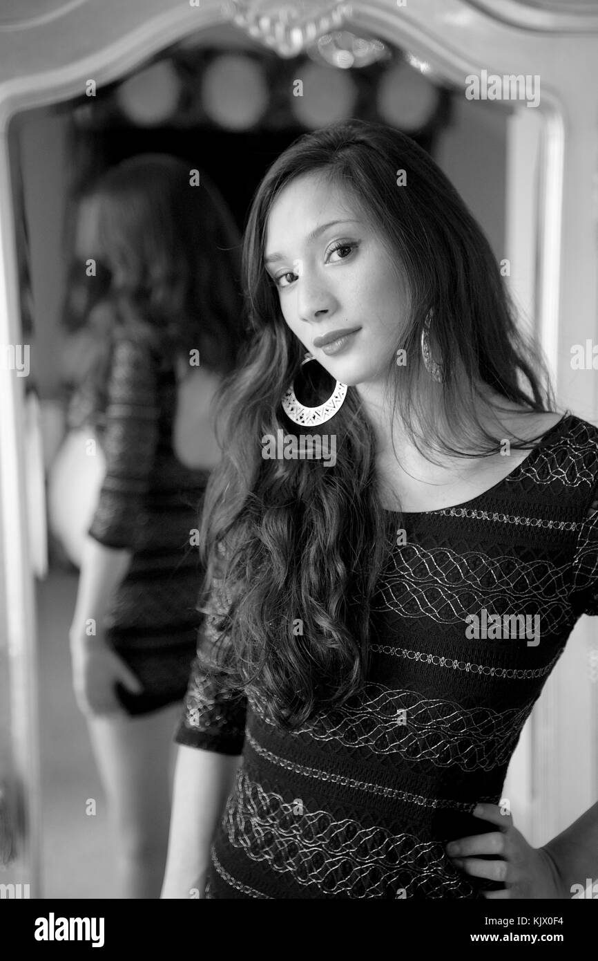 Beautiful brunette girl stood in front of a mirror in a black mini ...