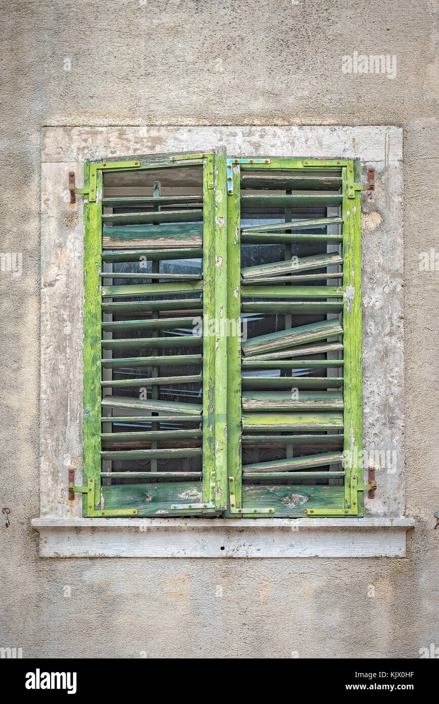 Old green shutters in need of repair cover a window in Kotor's old town in Montenegro. Stock Photo