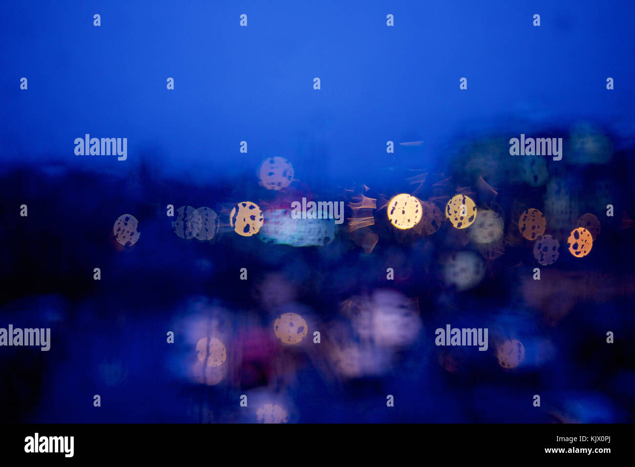 View through a window at night with raindrops and bokeh effect on ...
