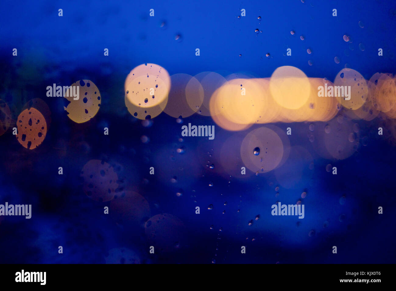 View through a window at night with raindrops and bokeh effect on ...