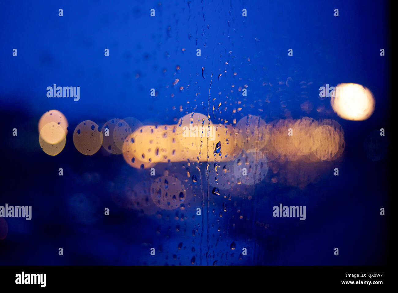 View through a window at night with raindrops and bokeh effect on ...