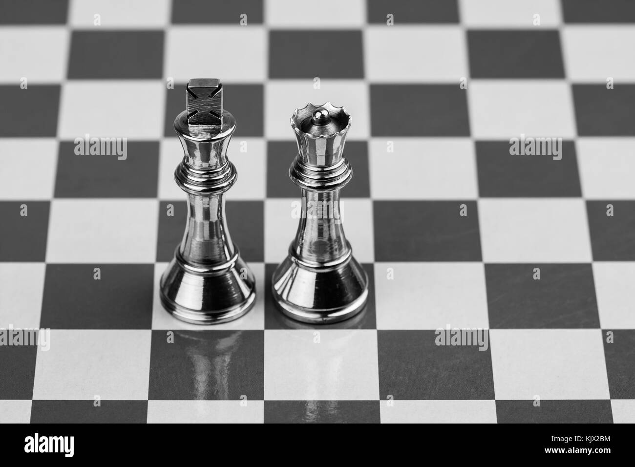 King and Queen - Rugged brass chess king and queen pieces on a chess board. Stock Photo