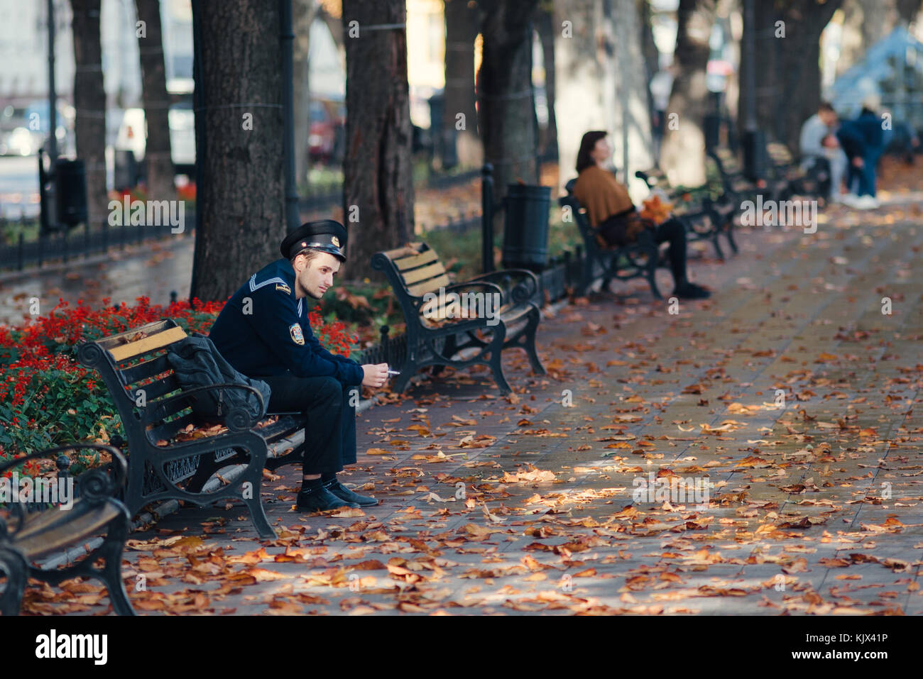 a man in a military uniform sits on a park bench to smoke a cigarette in Odessa, Ukraine Stock Photo