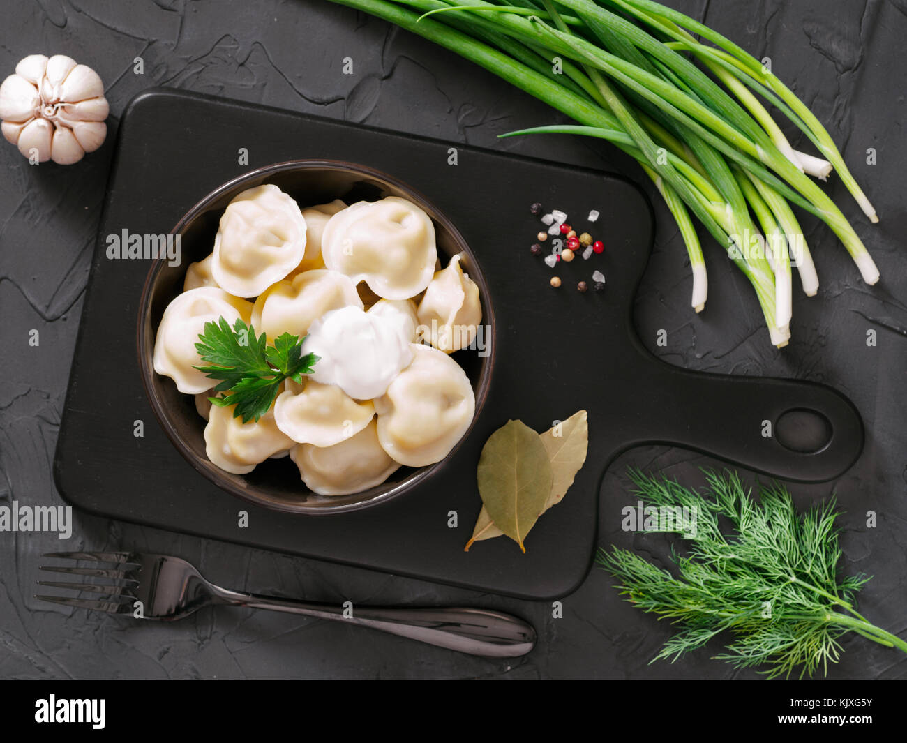 Traditional russian pelmeni, ravioli, dumplings with meat on black ...
