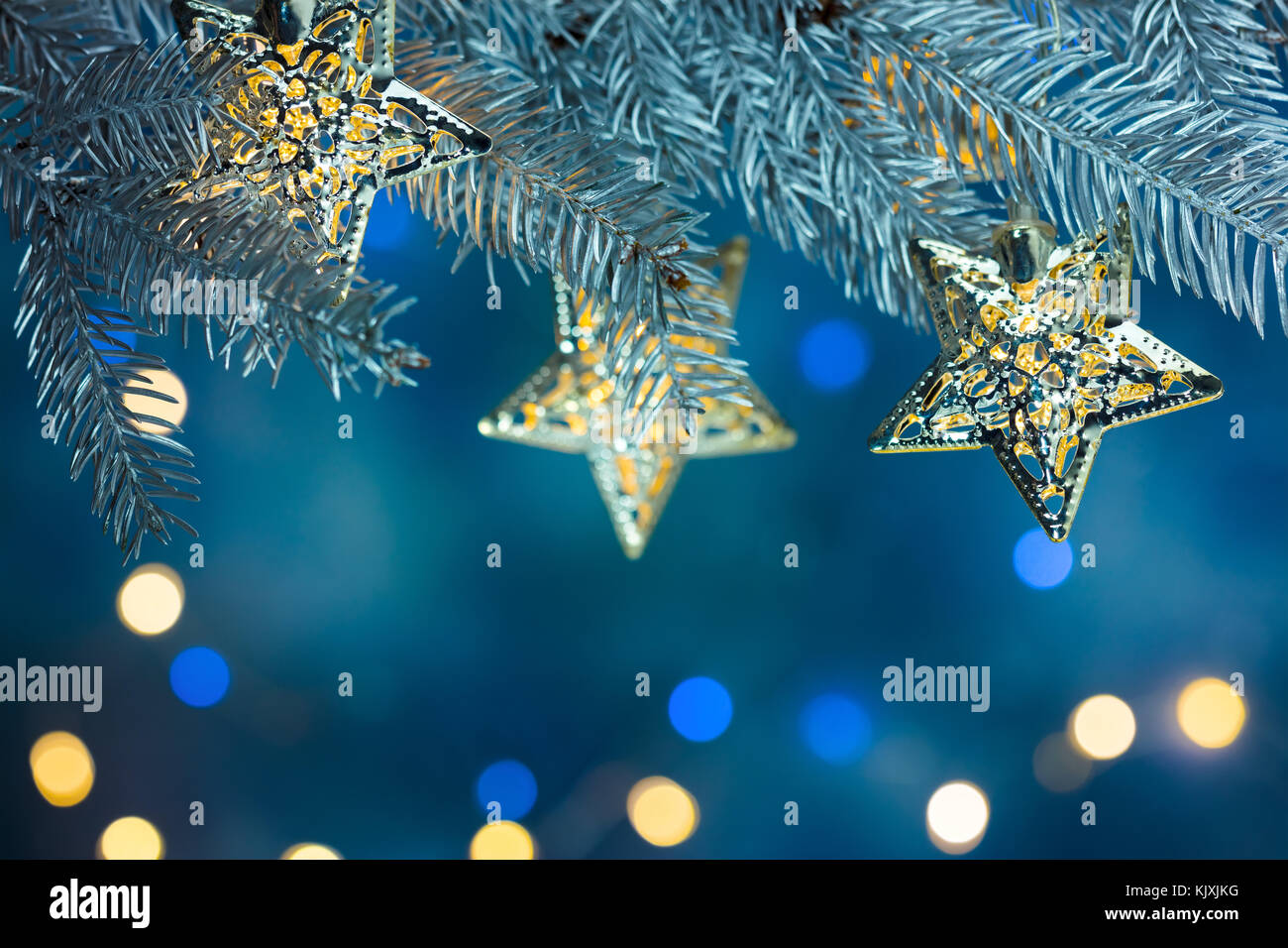 fir tree branch decorated with garlands on blue background with blurred ...