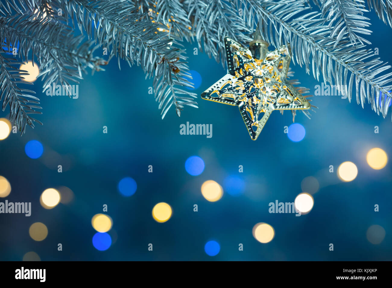 christmas tree branch with star decoration on blurred blue background ...