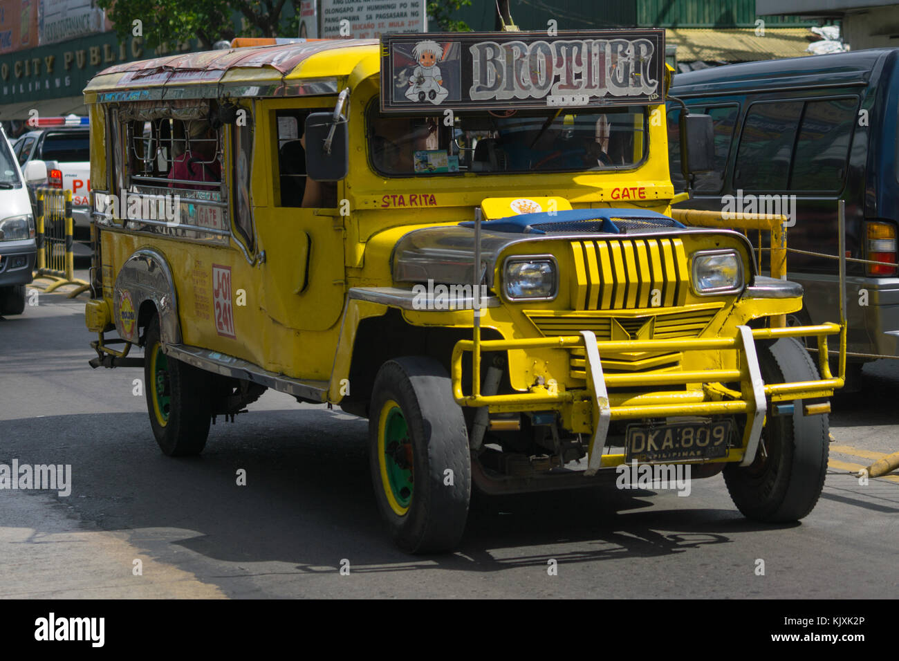 A yellow Public Utility Jeepney Vehicle with passengers being driven in Olongapo City,Bataan,Philippines Stock Photo
