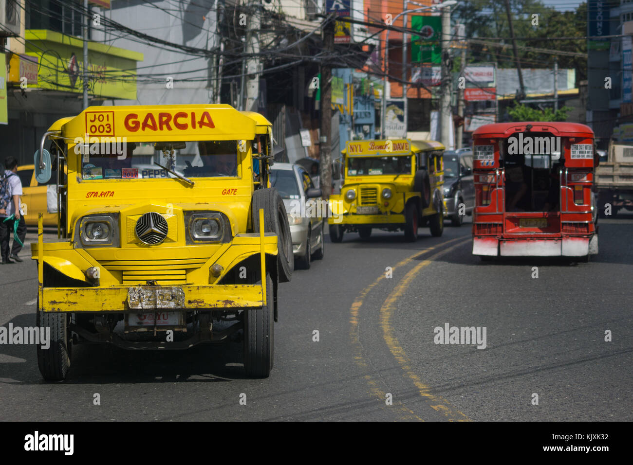 A yellow Public Utility Jeepney Vehicle with passengers being driven in Olongapo City,Bataan,Philippines Stock Photo