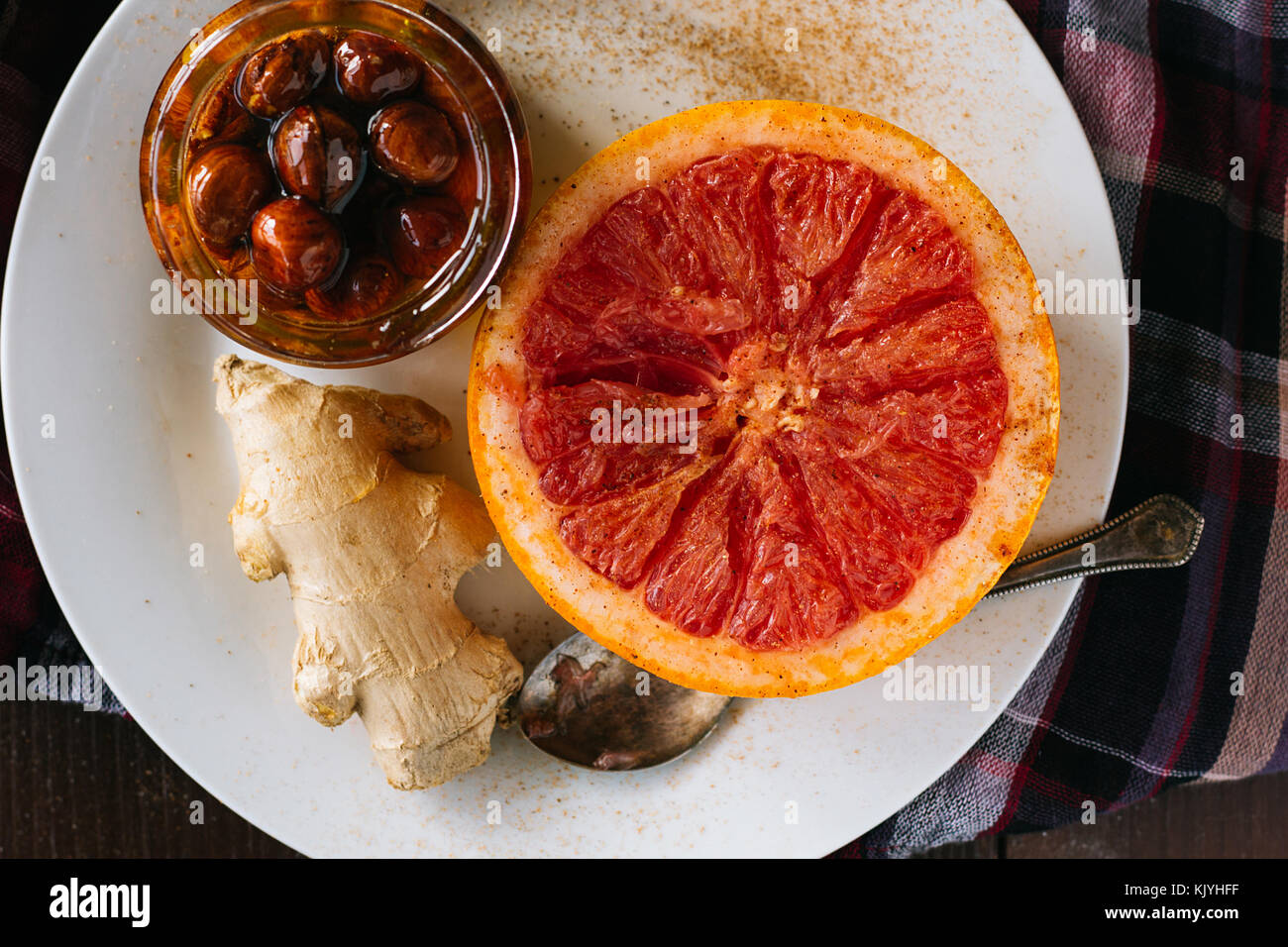 Broiled grapefruits, ginger and honey on white dish top view selective focus Stock Photo