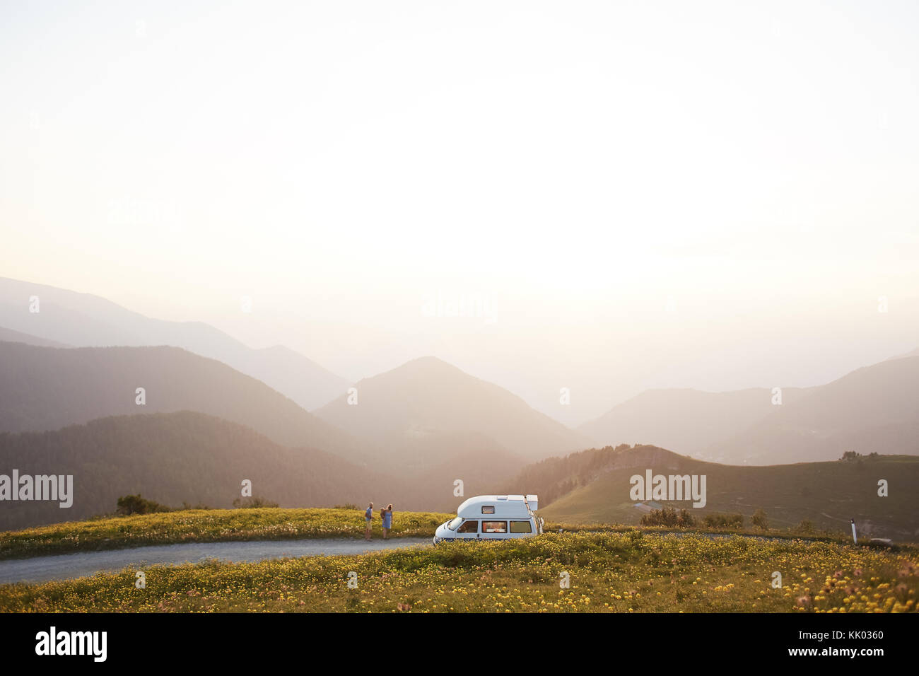 A beautiful bus stands on the background of the mountains near which stands the family Stock Photo