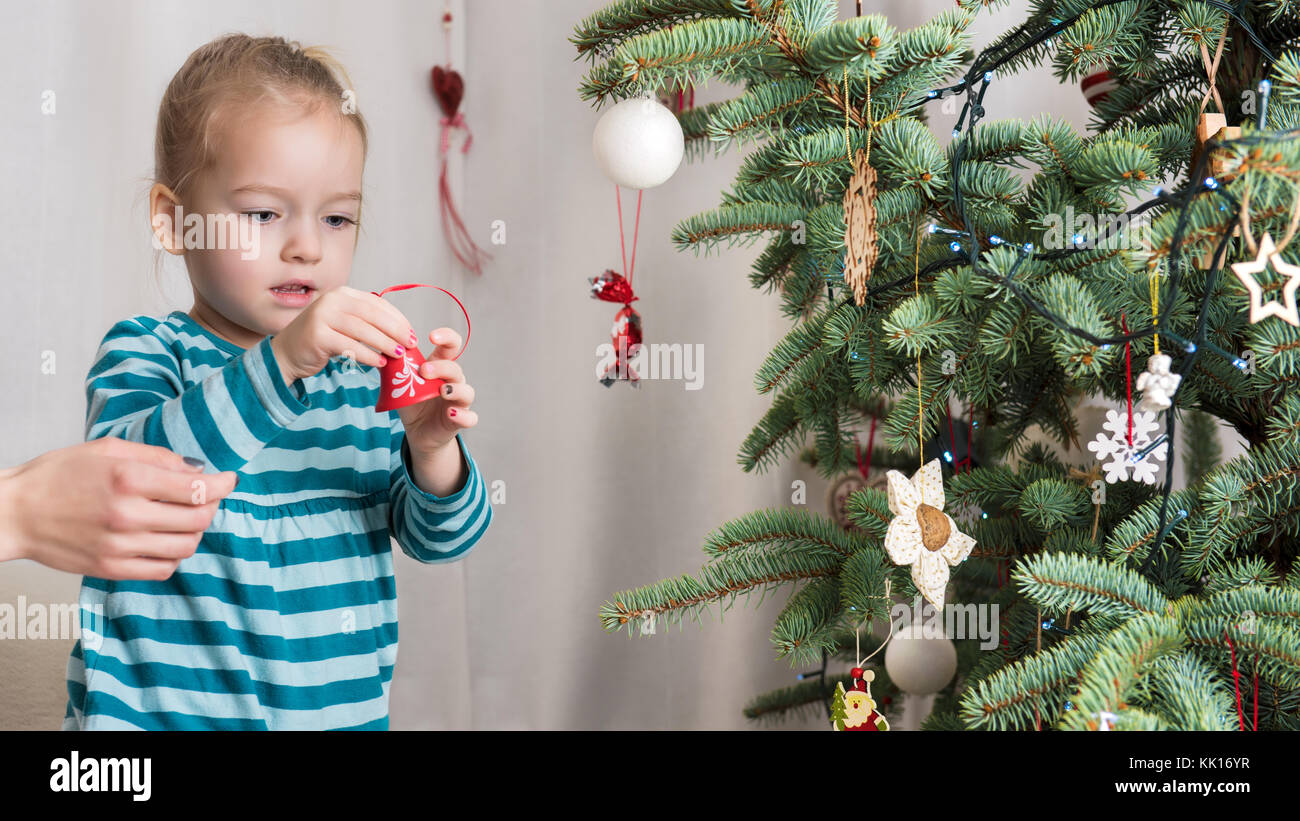 Cute blond preschool girl decorating christmas tree. Authentic family xmas time concept Stock Photo