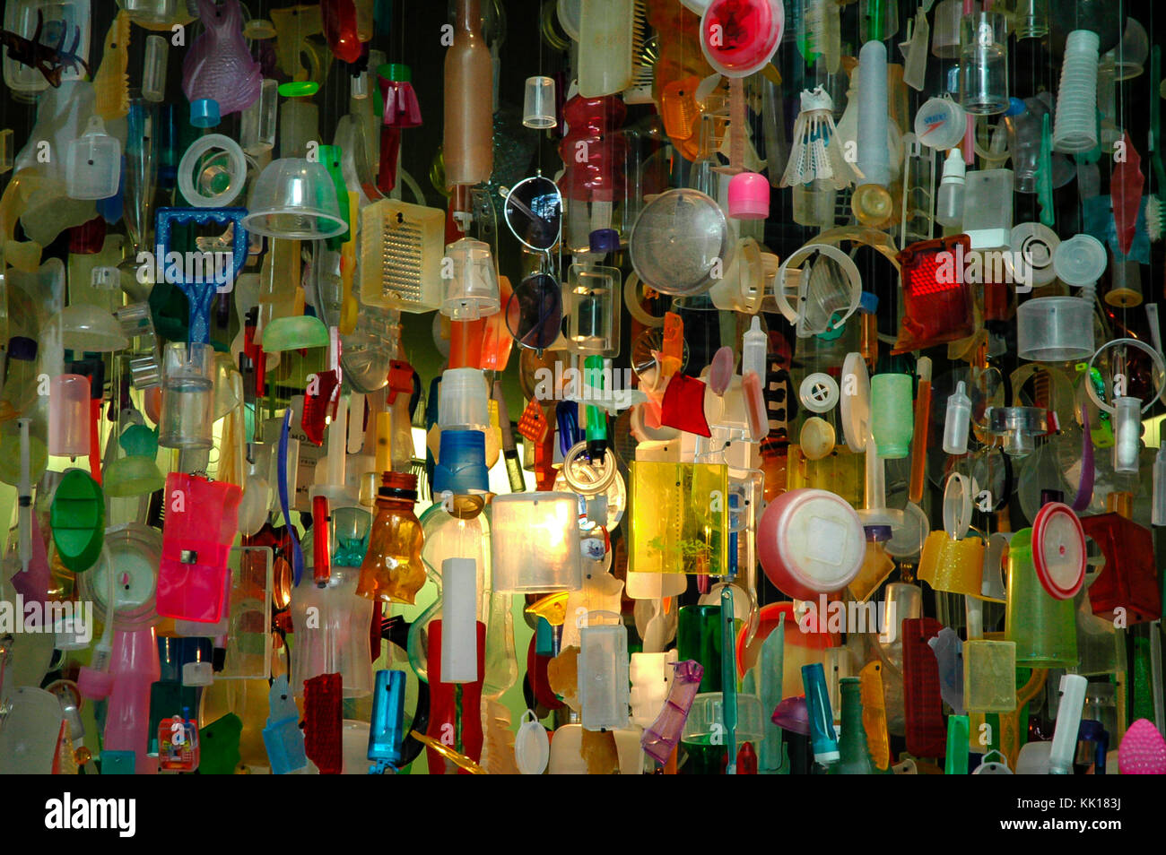 Window display with mosaic of colourful pieces of plastic sun glasses toys cups hanging on a string. Art installation. Plastic awareness concept. Stock Photo