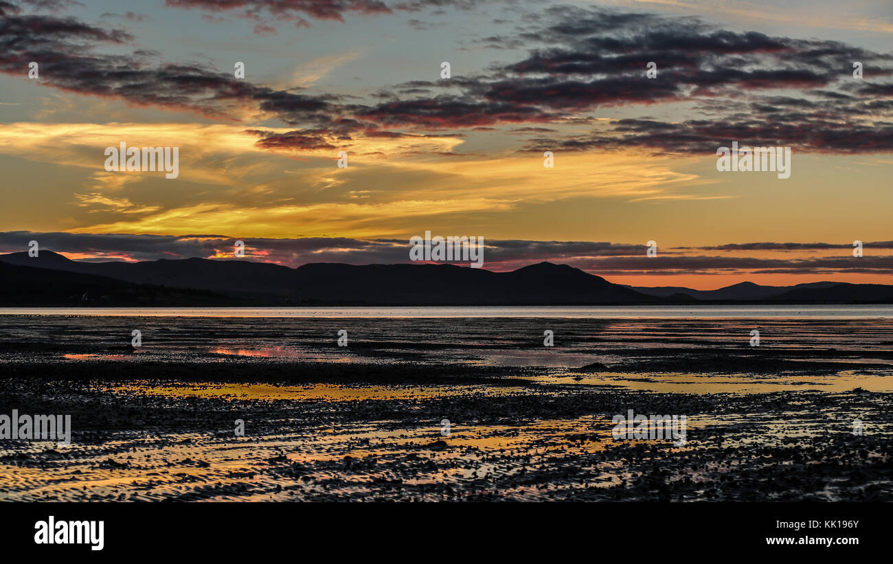 The setting sun creates an explosion of colour over and around the Struie Hill and Dornoch Bridge in NW Scotland. Stock Photo
