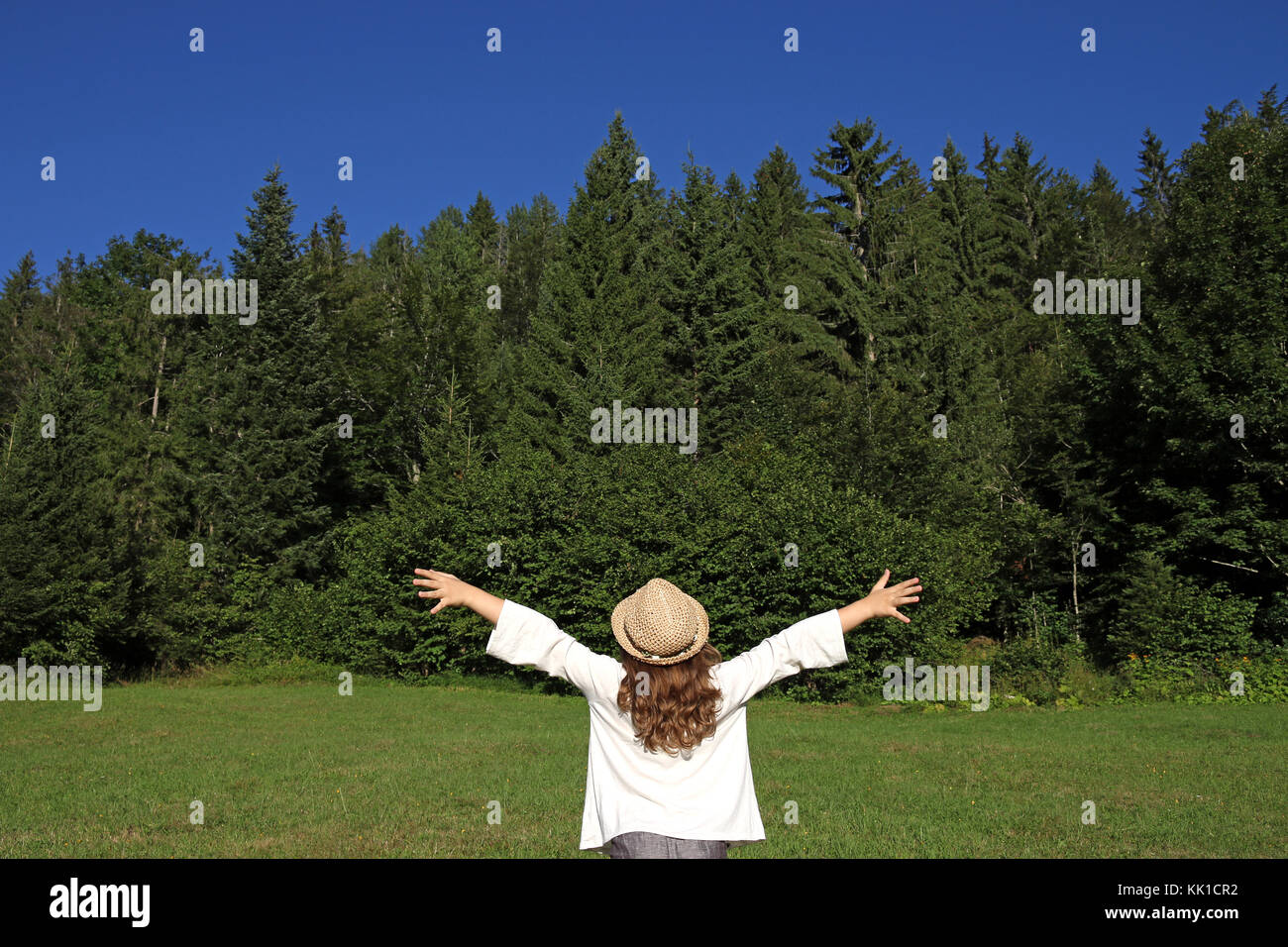 little girl with hands up looking at the forest Stock Photo