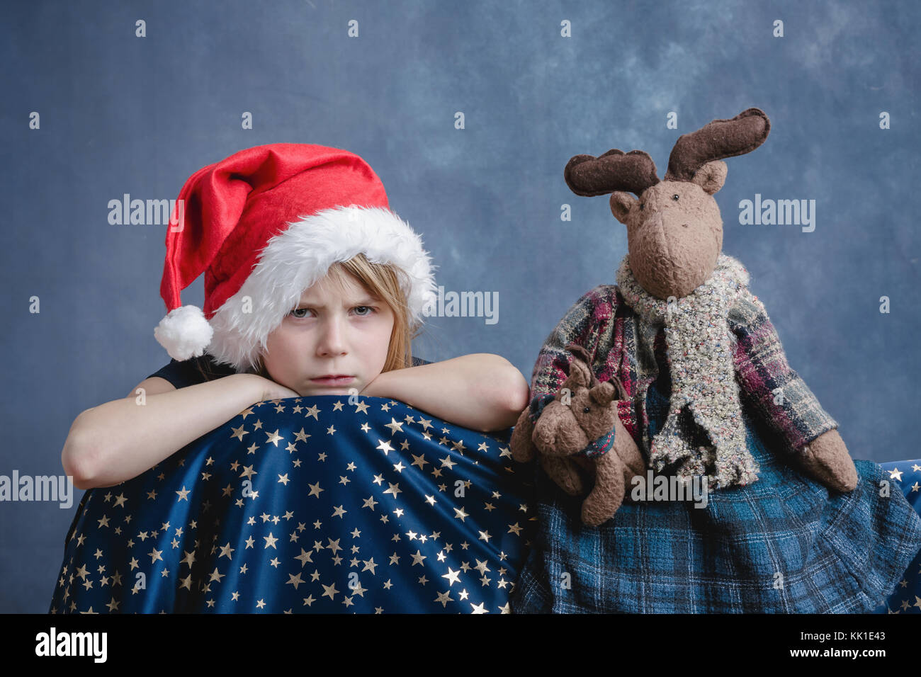 7-years old girl in Santa Hat lookig unhappy. Stock Photo