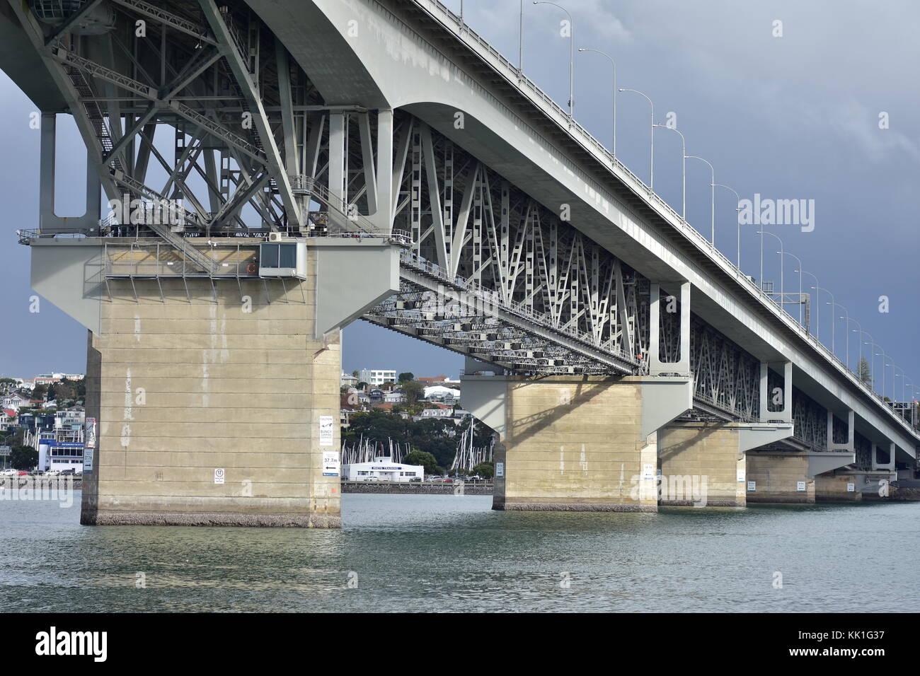 Auckland Harbour Bridge with steel structure and smooth concrete pillars in waters of Waitemata Harbour connecting Auckland CBD with North Shore City. Stock Photo