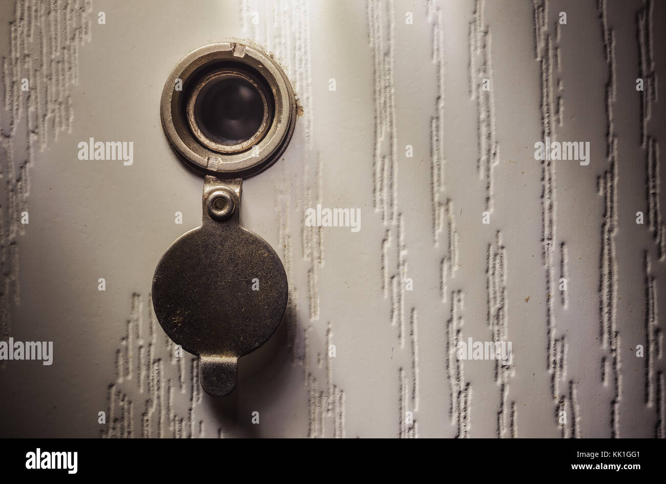 Closeup view on details of an old peephole in white wooden doors Stock
