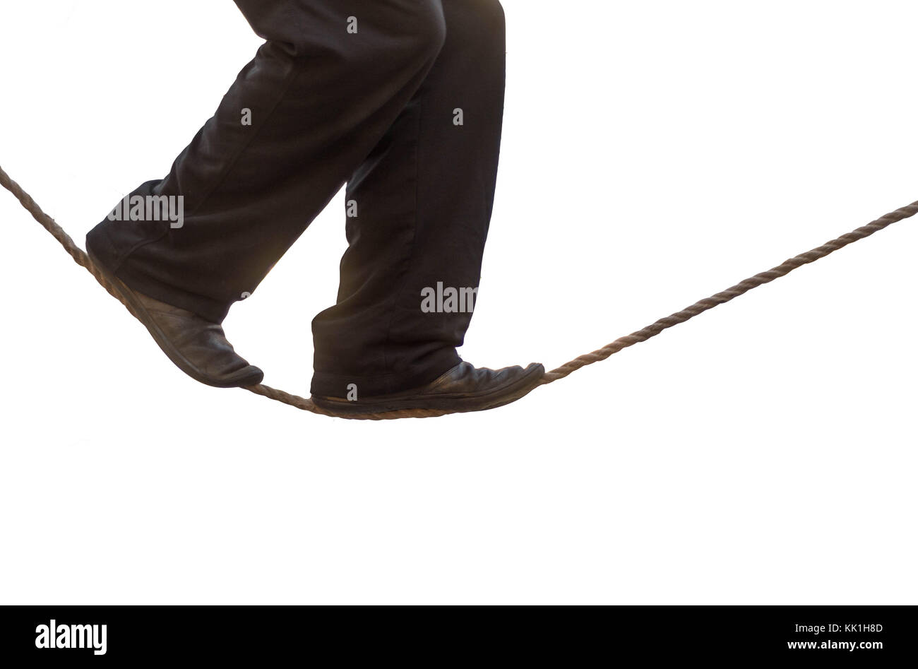 Tight rope walker's legs isolated. Feet of acrobat balancing on rope against white background Stock Photo