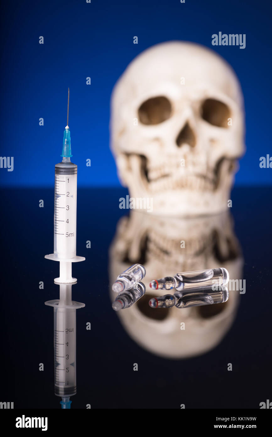 Blurry Skull and syringe, isolated on black blue background with glossy reflection Stock Photo