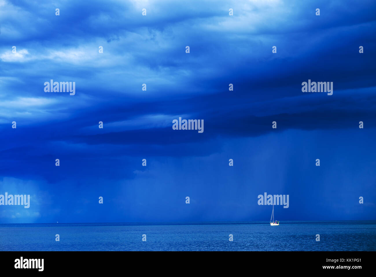 Sailing boat at stormy sea horizon with dark rainy clouds in background ...
