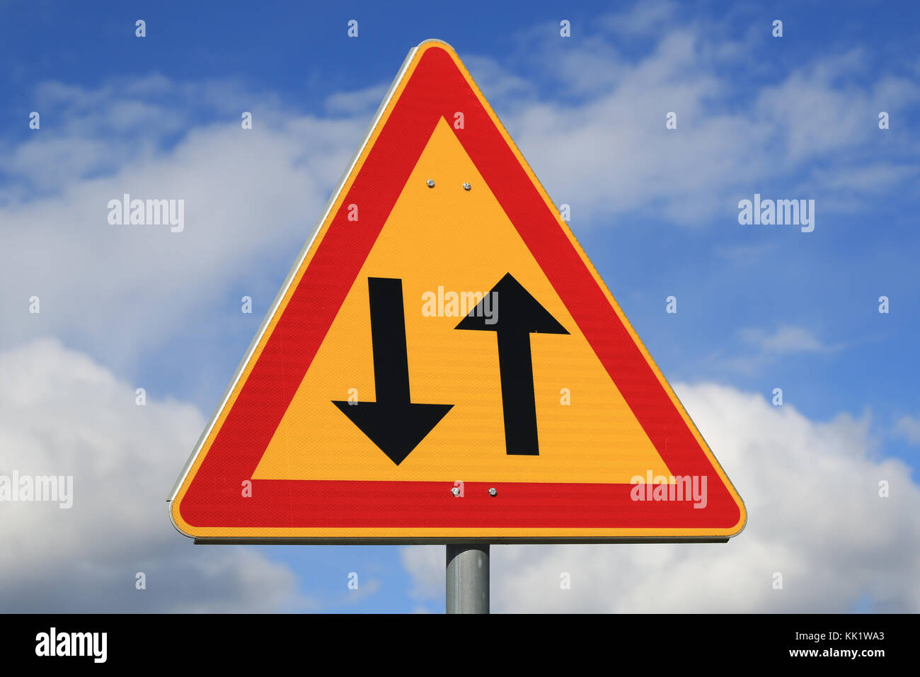 Sign two way traffic against blue sky with some clouds. Stock Photo