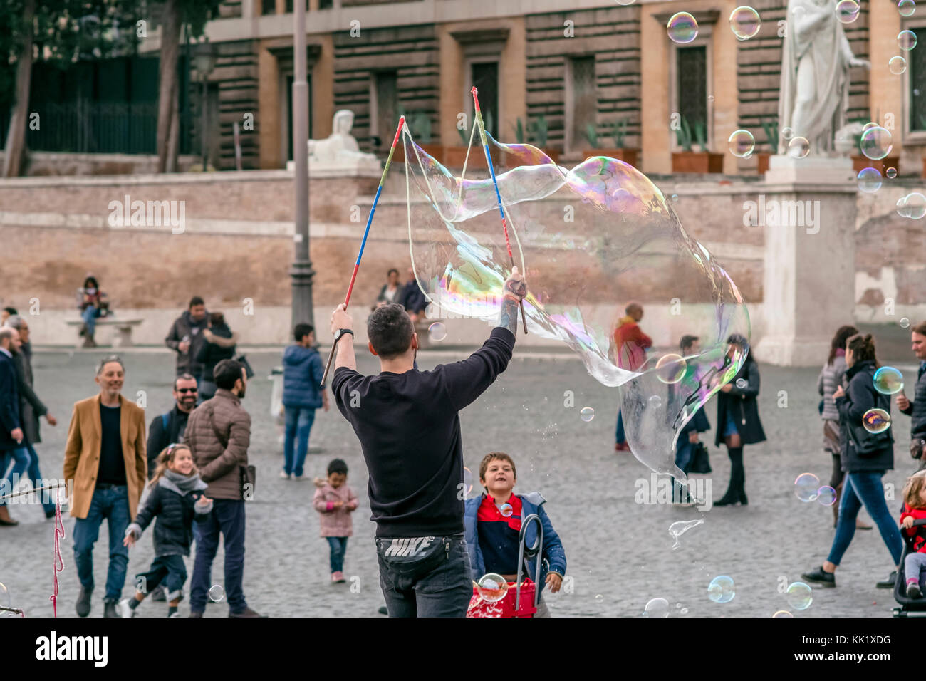 An artist is making big soap bubbles for kids with special device in ...