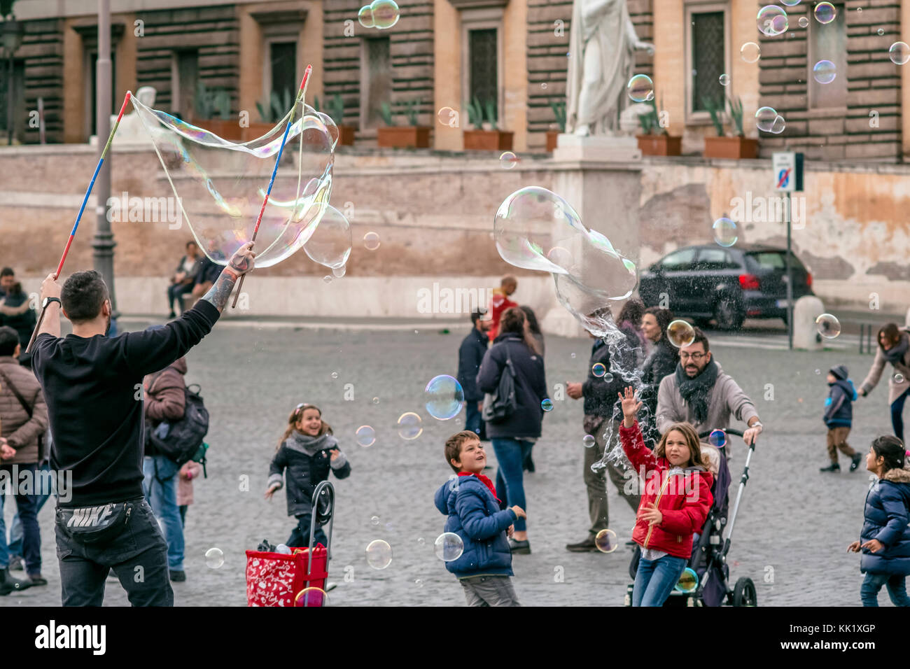 An artist is making big soap bubbles for kids with special device in ...