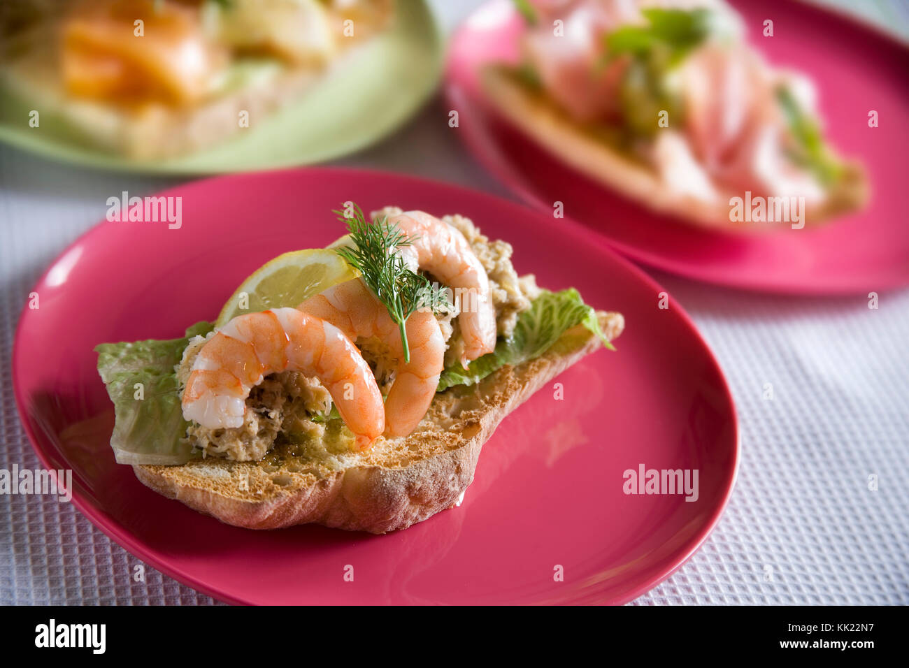 King prawn bruschetta with crab, lettuce, lemon, dill and olive oil served on colourful plate Stock Photo
