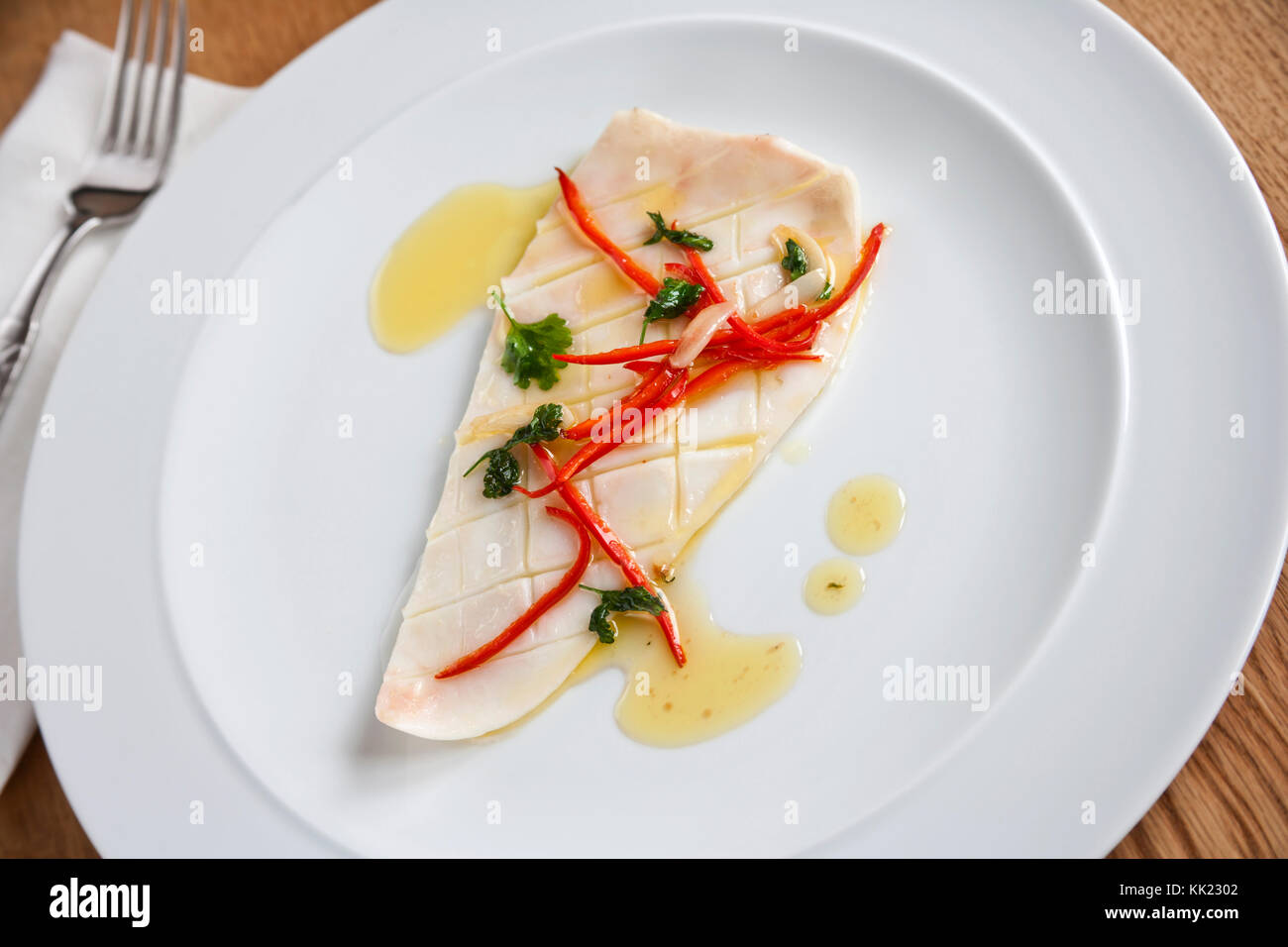 Cooked squid body envelope with red chilli and olive oil served on white plate Stock Photo
