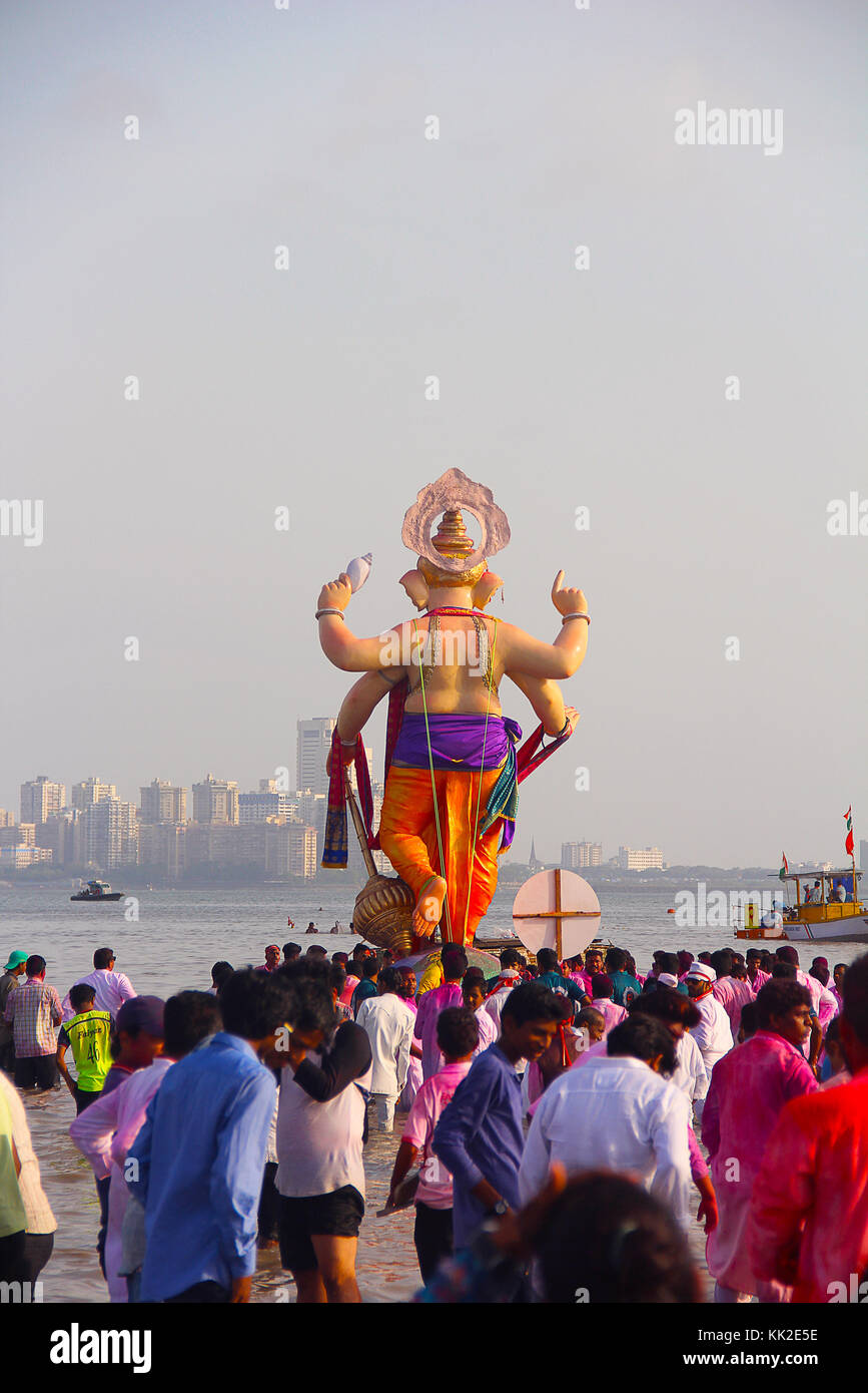 Back view of huge standing Ganapati idol with crowd, Ganapati visarjan, Girgaon Chowpatty, Mumbai Stock Photo