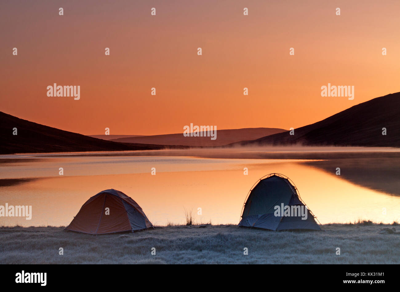 Two tents pitched beside a remote Scottish loch, photographed at dawn. Stock Photo