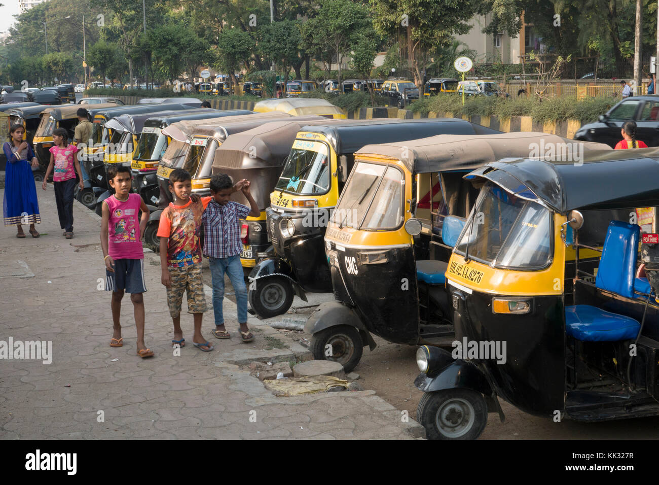 Children stand next to parked auto rickshaws (tuk tuk) in Versova, Mumbai, India Stock Photo