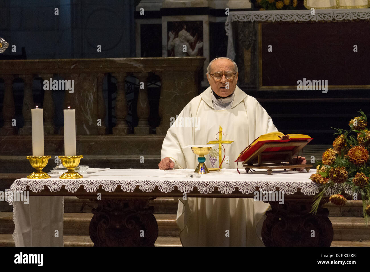 Pavia, Italy. November 11 2017. A priest celebrating a holy mass in Duomo di Pavia (Pavia Cathedral). He is praying over the bread and wine on the alt Stock Photo