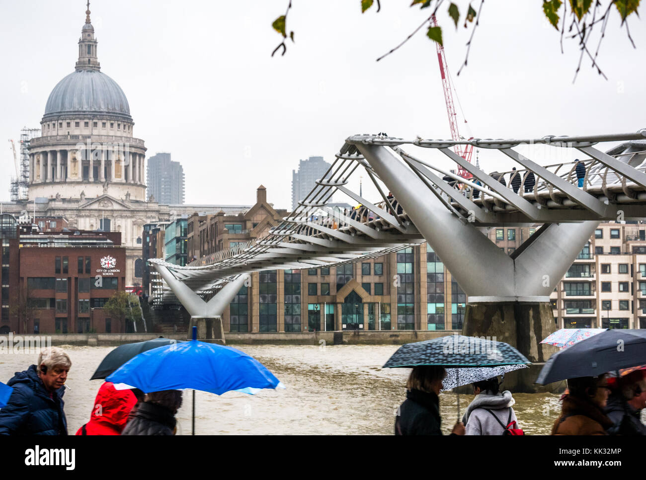 People passing by with colourful umbrellas on rainy day, River Thames, Millennium Bridge, London, England, UK, with St Pauls Cathedral Stock Photo