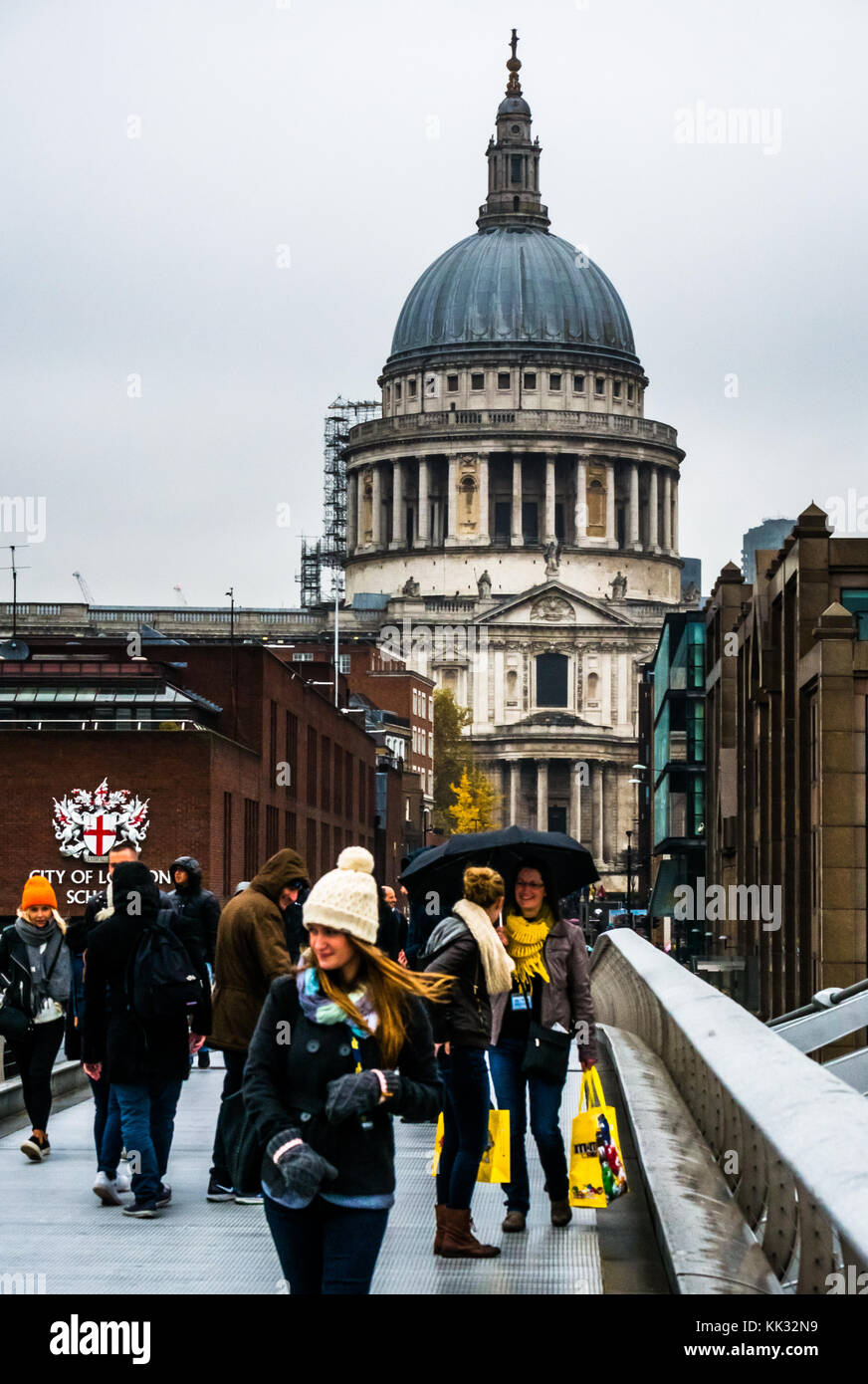 People walking on Millennium Bridge on rainy day to St Pauls Cathedral and City of London school, Thames, England, UK Stock Photo