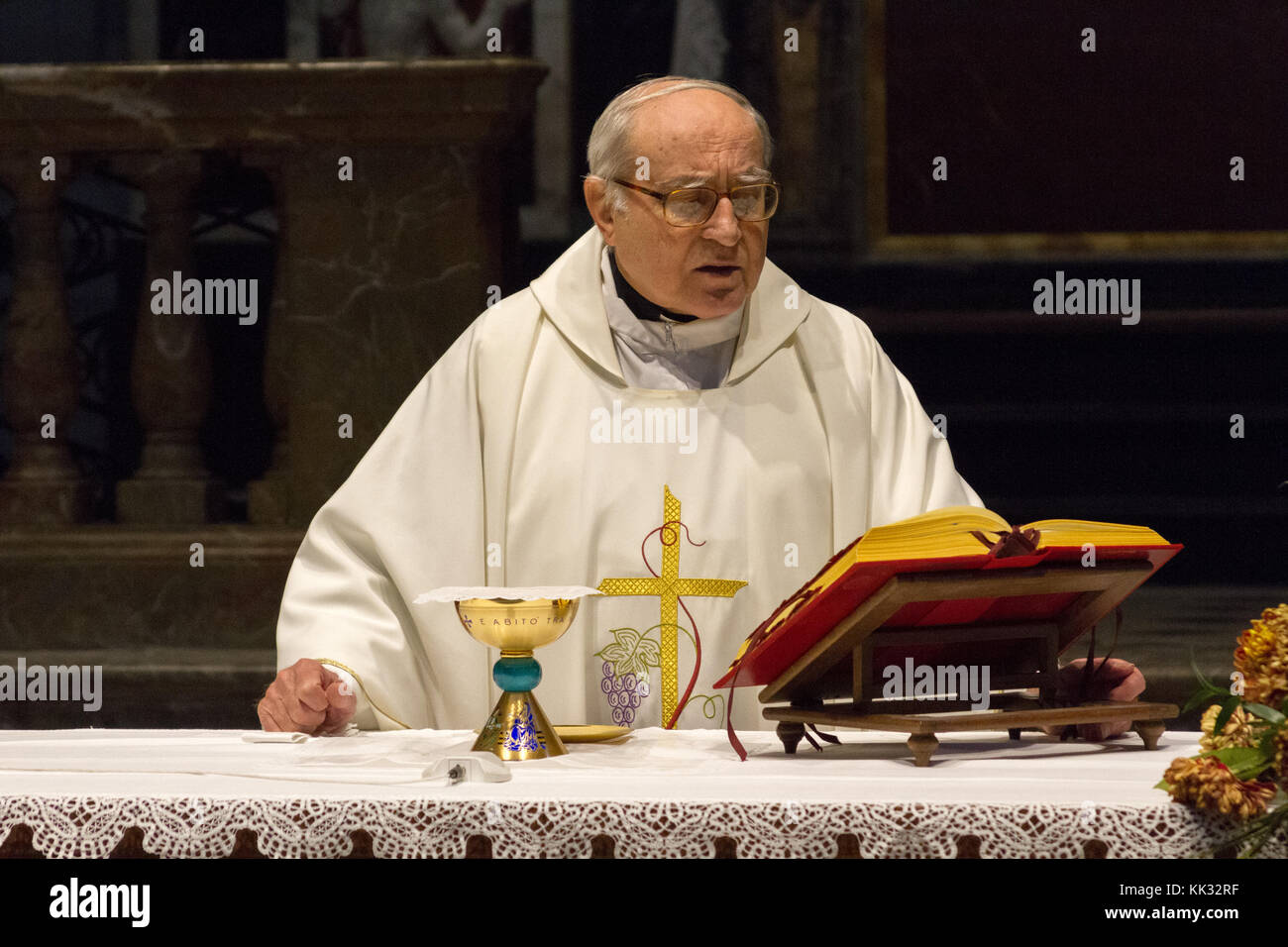 Pavia, Italy. November 11 2017. A priest celebrating a holy mass in Duomo di Pavia (Pavia Cathedral). He is praying over the bread and wine on the alt Stock Photo