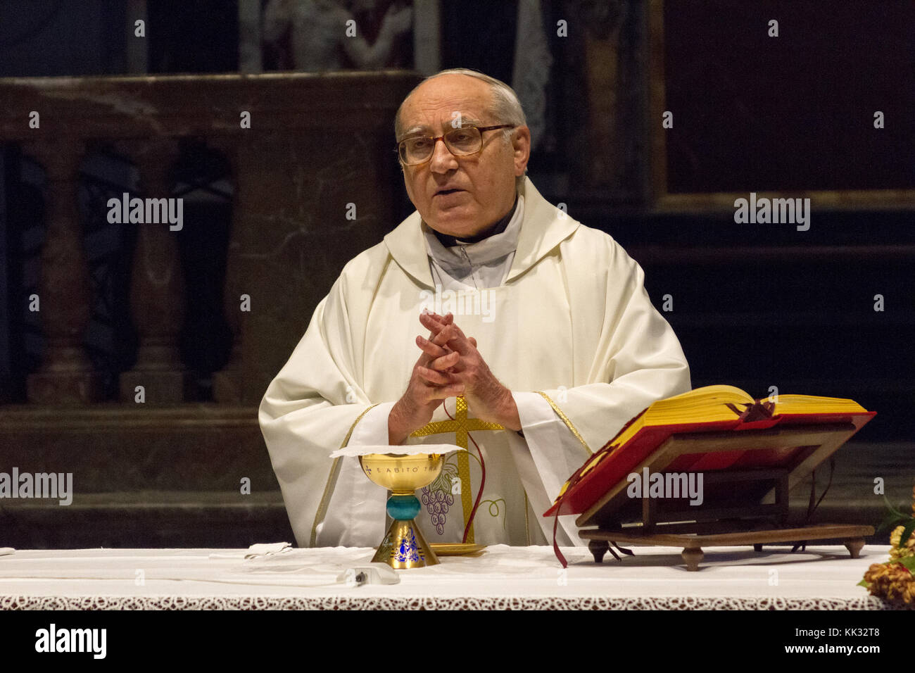 Pavia, Italy. November 11 2017. A priest celebrating a holy mass in Duomo di Pavia (Pavia Cathedral). He is praying over the bread and wine on the alt Stock Photo