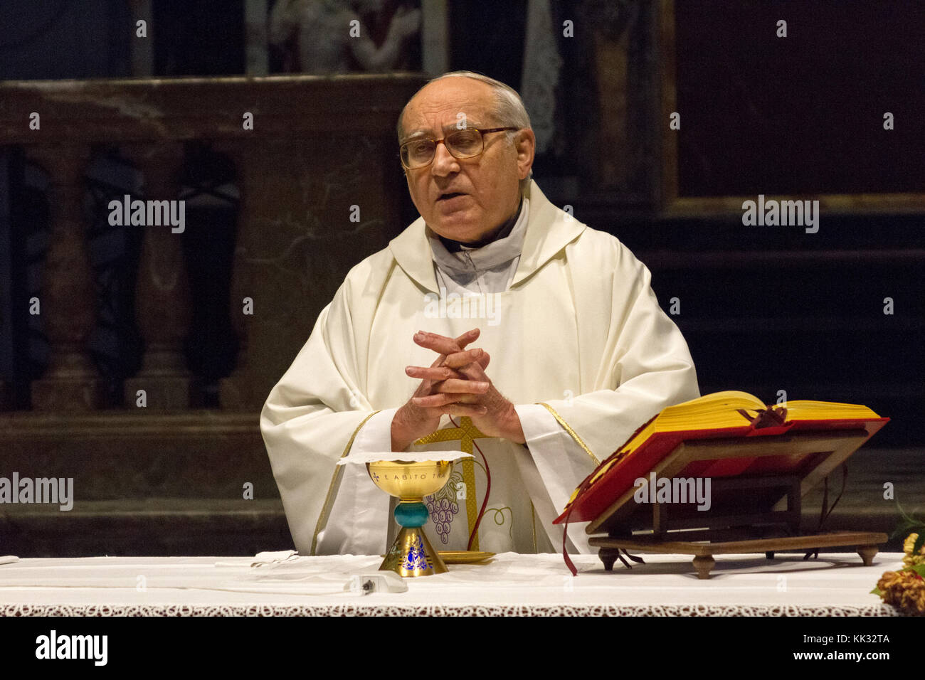 Pavia, Italy. November 11 2017. A priest celebrating a holy mass in Duomo di Pavia (Pavia Cathedral). He is praying over the bread and wine on the alt Stock Photo