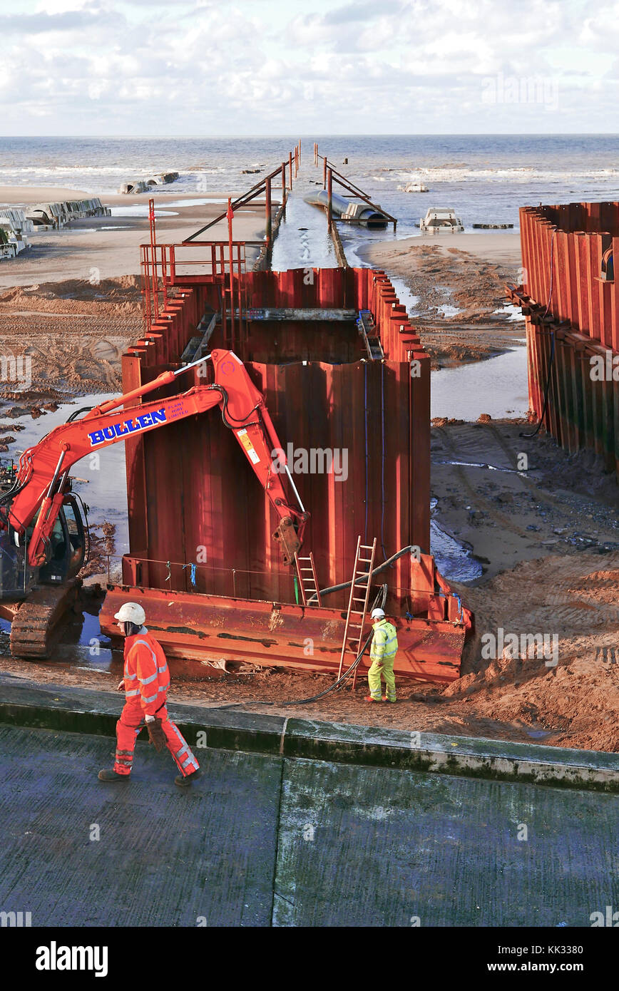 Marine engineers working on cofferdams at low tide during construction of offshore pipeline Stock Photo