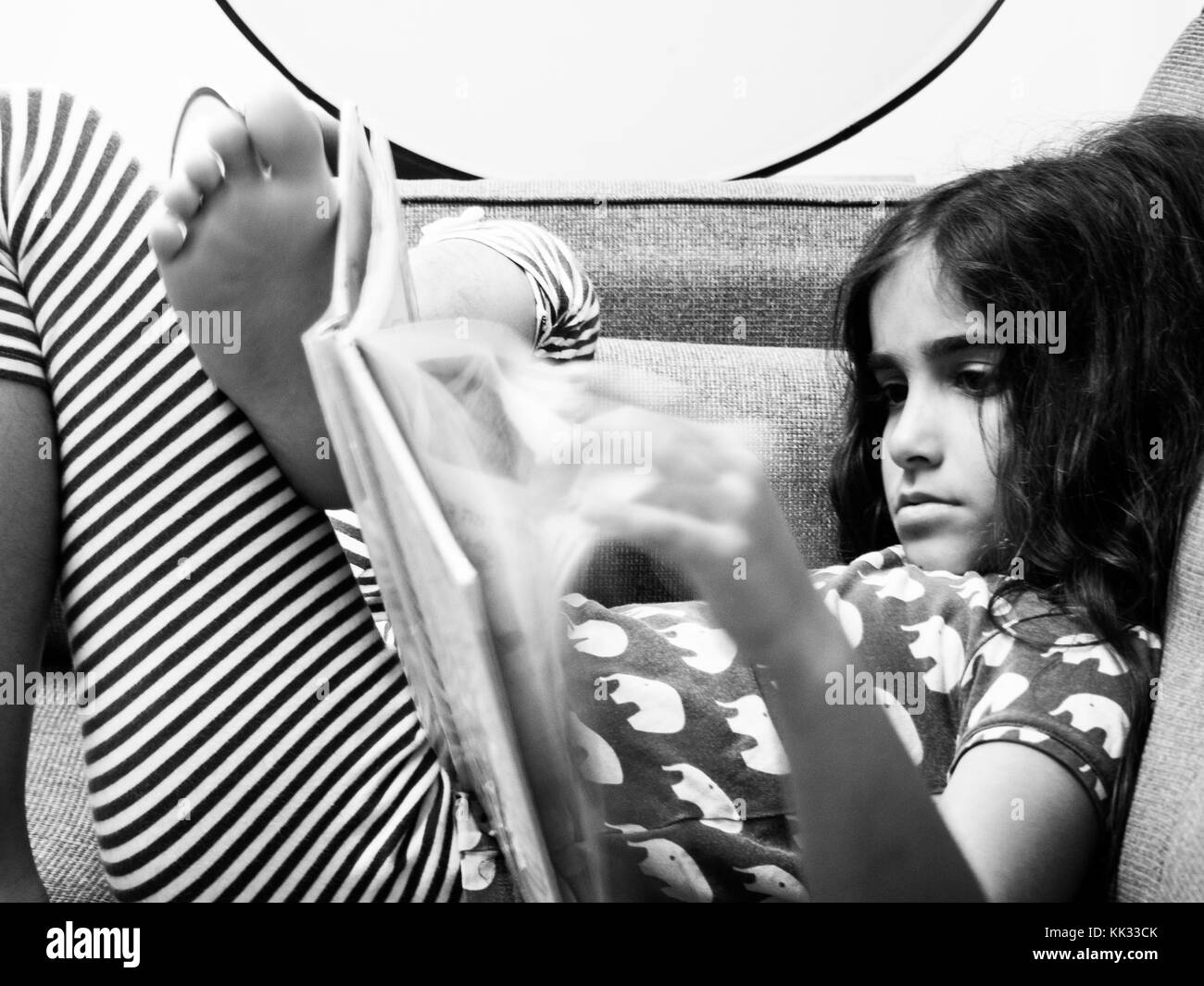 girl reading a book on a sofa Stock Photo