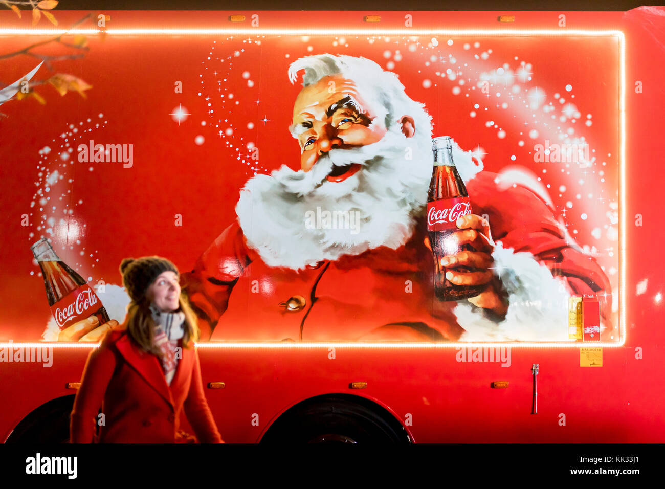 Woman in front of Coca-Cola Christmas truck in the United Kingdom depicting  traditional Santa Claus or Father Christmas holding a bottle of Coke Stock  Photo - Alamy