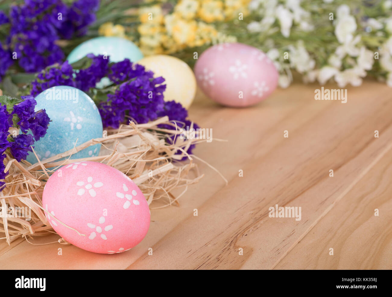 Colorful easter eggs and flowers on a wood surface Stock Photo - Alamy